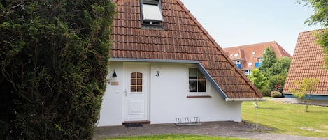Ein kleines, eingeschossiges Haus mit einem geneigten Dach und einer weißen Tür.