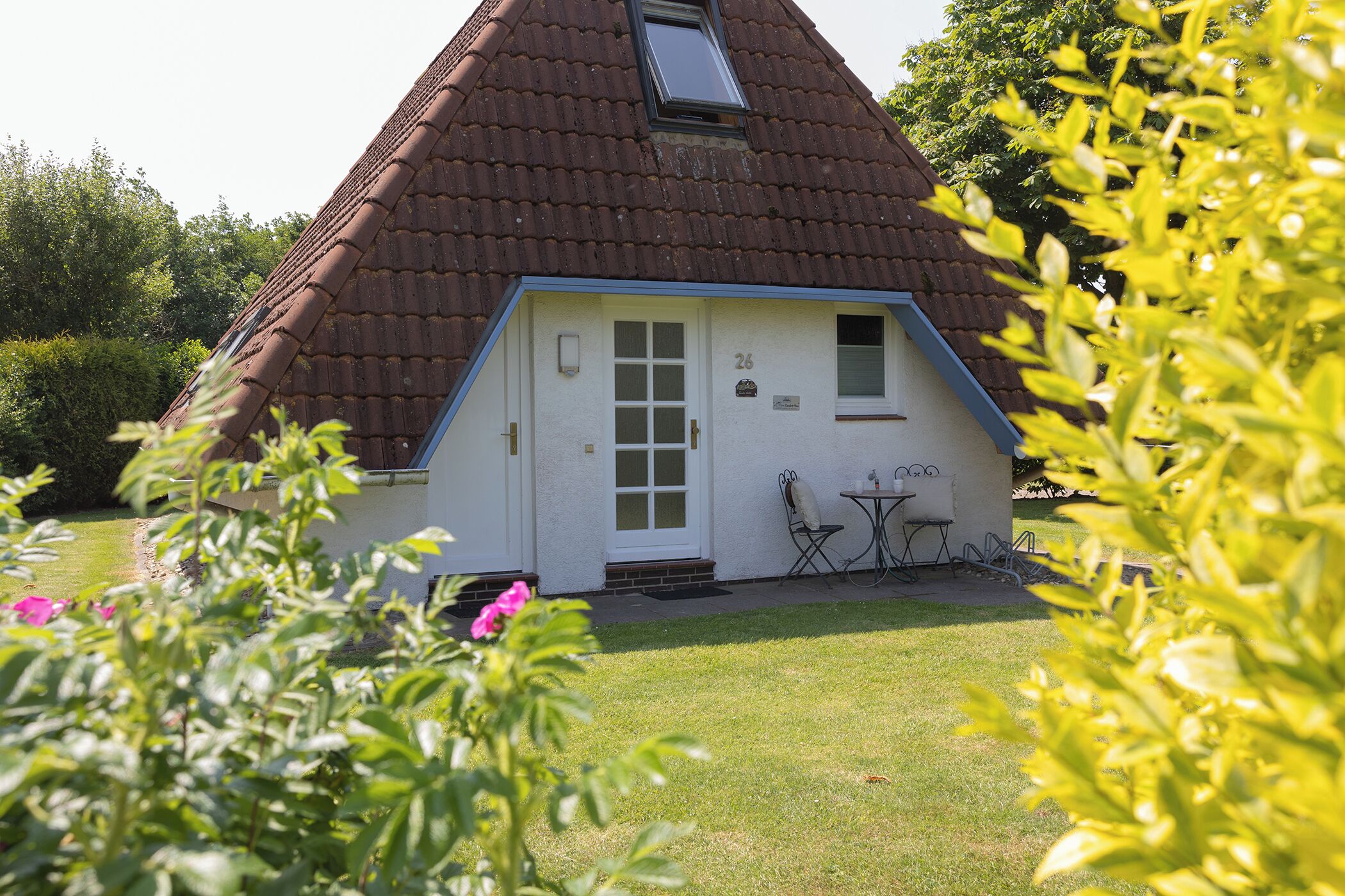 Un bâtiment blanc avec un toit marron, une petite fenêtre et une porte.