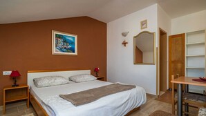 Een slaapkamer met een bed, bedlampen, een schilderij, een spiegel, een houten bureau en een stoel.
