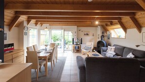 A spacious living area with a dining table, sofa, and fireplace. - Vacation home Westertill 15 with tidal magic and at the cutter harbor. (Wurster Nordseeküste)