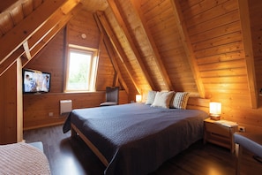 Une chambre confortable située dans les combles, avec un grand lit, une télévision et une fenêtre.
