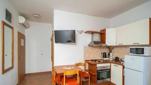 Une cuisine compacte comprenant une table à manger, des chaises, une cuisinière, un four à micro-ondes et un téléviseur.