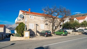 Une vue de rue avec un immeuble sur lequel on peut voir une antenne parabolique, un arbre et des voitures garées.