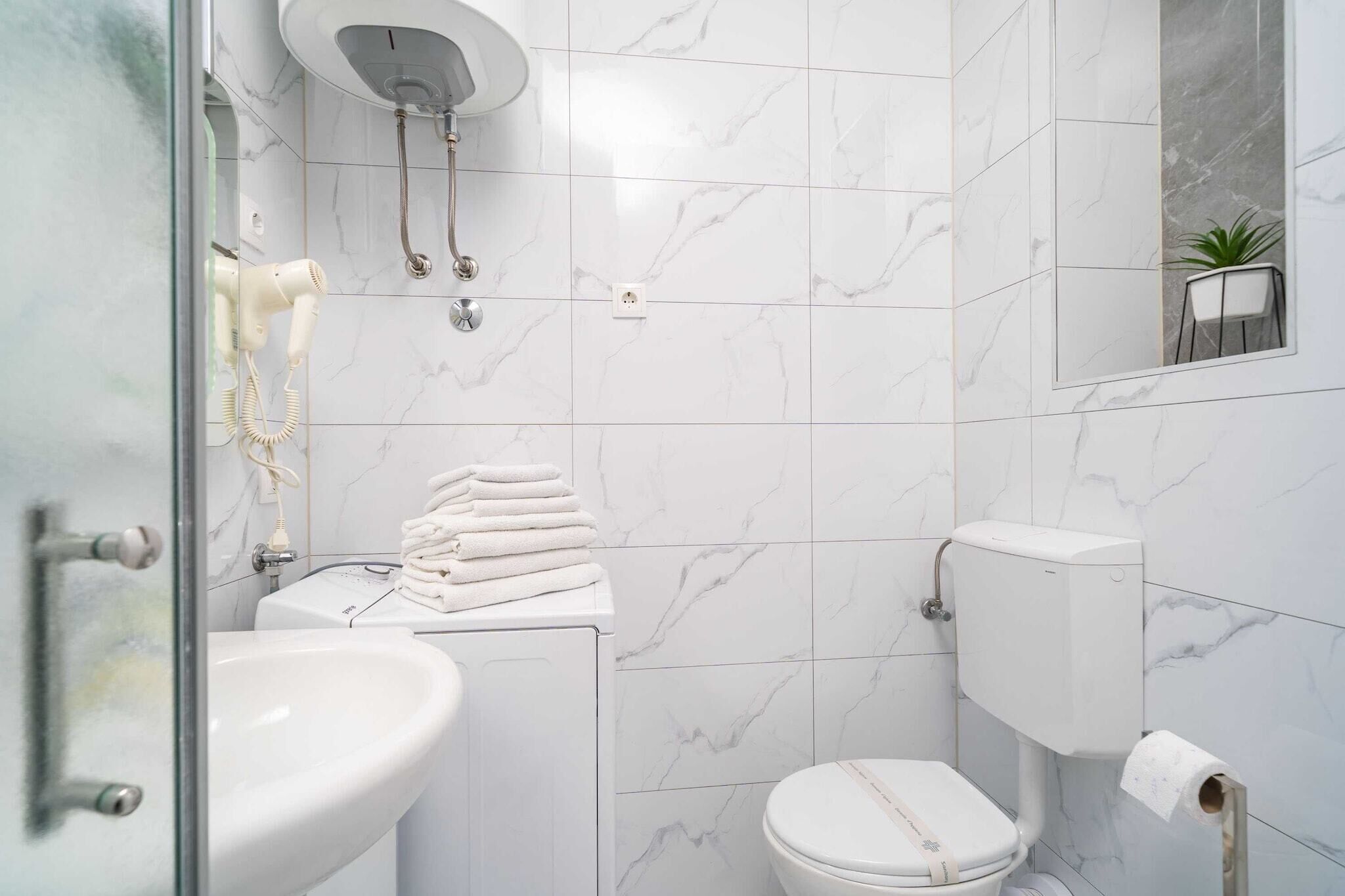 Un bagno moderno con box doccia in vetro, un water bianco e un lavandino.