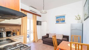 Un espacio habitable compacto con kitchenette, comedor y sofá.