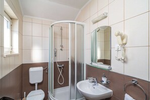 A modern bathroom with a glass shower enclosure, a toilet, a sink, and a hairdryer mounted on the wall. - Apartments Senjo - One Bedroom Apartment with Balcony with Sea View (Apartman 1) (Cavtat)