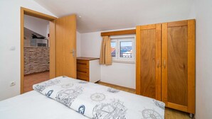 Ein Schlafzimmer mit Bett, Holzschrank und Fenster mit Aussicht.