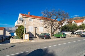 A street view with a building featuring a satellite dish, a tree, and parked cars. - Apartments Senjo - One Bedroom Apartment with Balcony with Sea View (Apartman 1) (Cavtat)