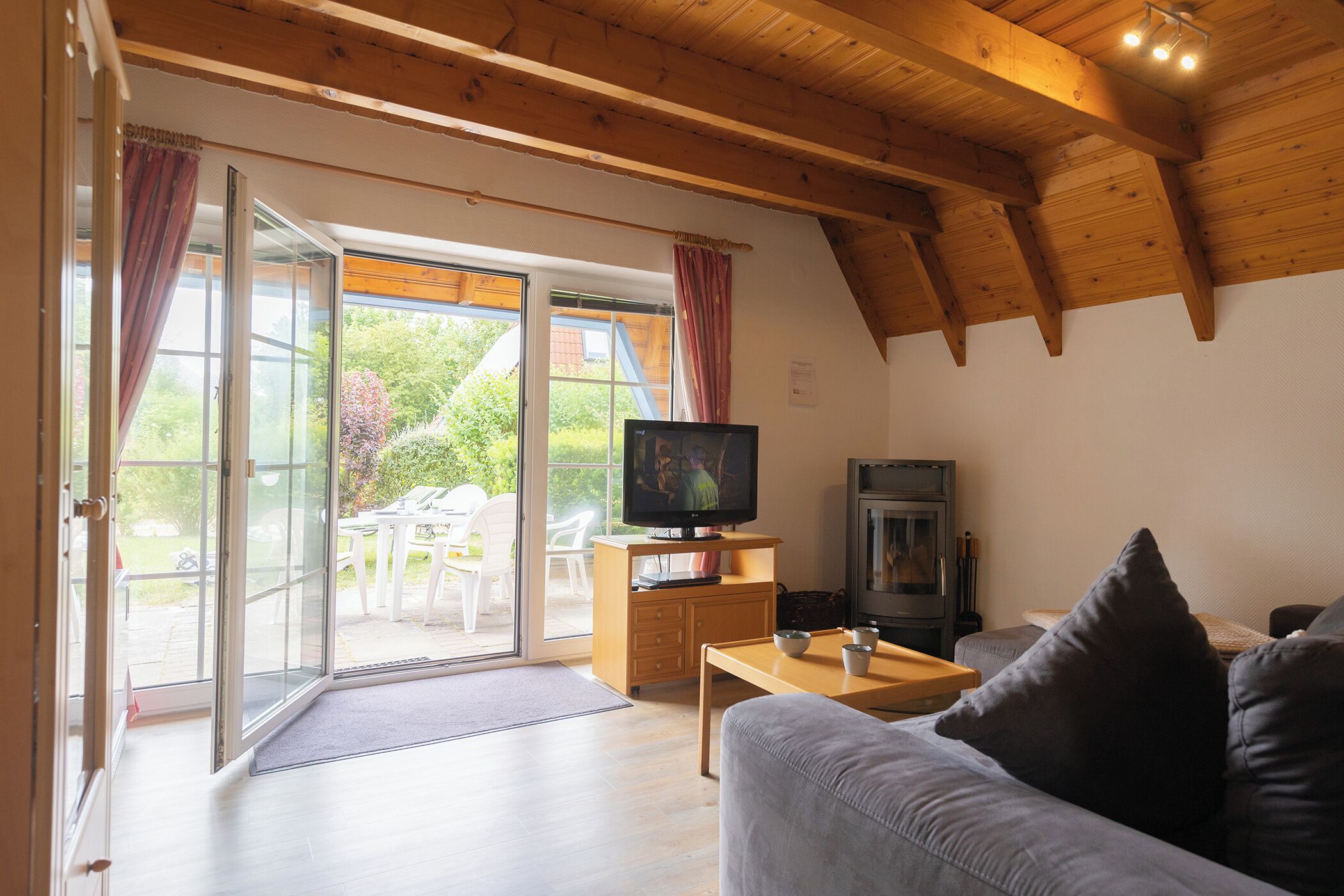 A living room with a television, wooden furniture, and a sliding glass door leading to an outdoor area.