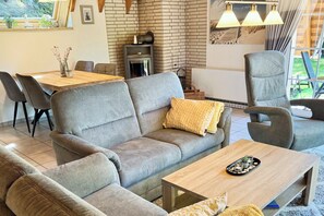 En moderne stue med en grå sofa, et træbord og spiseområde med et bord og stole.