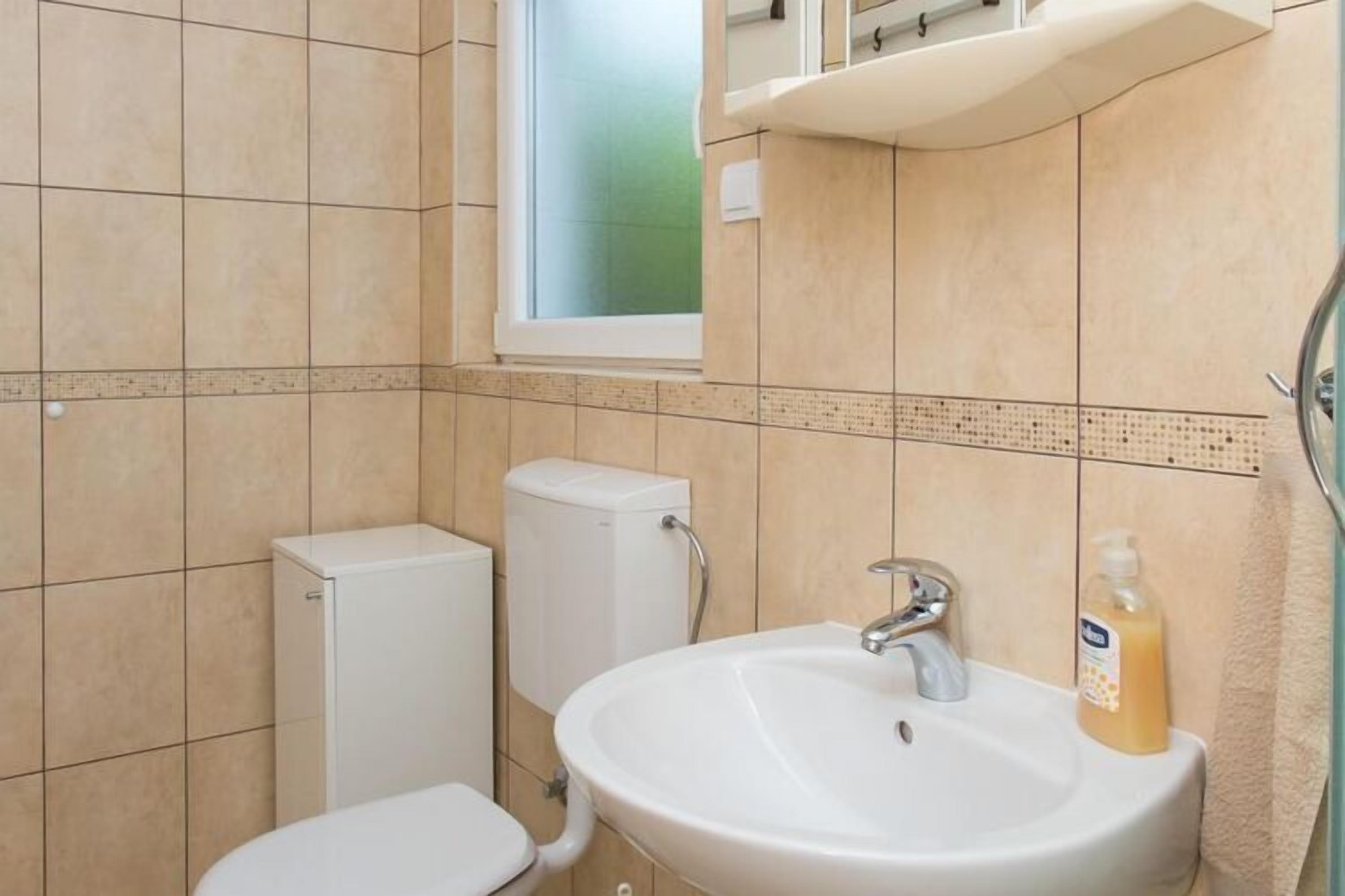 A bathroom with a toilet, a sink, and a window.