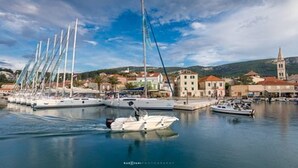 Un port de plaisance où sont amarrés plusieurs voiliers, un petit bateau à moteur et, au loin, une église dotée d’un clocher.