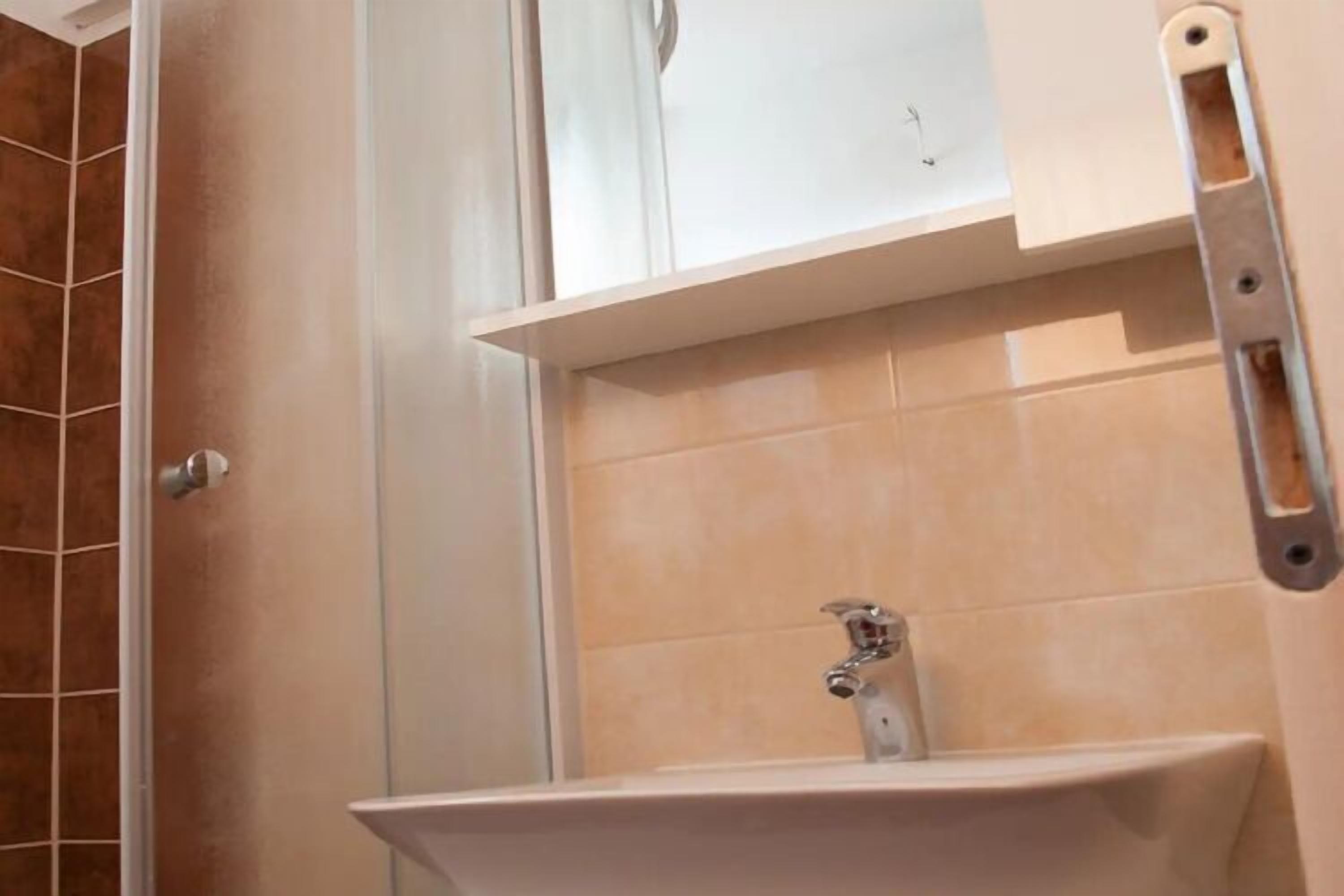 A bathroom with a sink, a mirror, and a shower area.