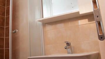 A bathroom with a sink, a mirror, and a shower area.