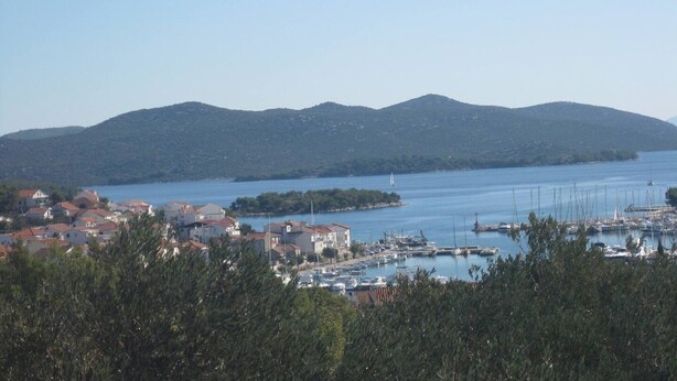 A coastal town with a marina, houses, and mountains in the background. - Apartments Paula - One Bedroom Apartment with Terrace 1 (Jezera)