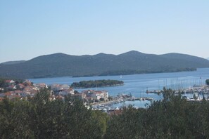 A coastal town with a marina, houses, and mountains in the background.