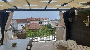 A balcony with a table and chairs, potted plants, and a view of buildings in the background. - Apartments Paula - One Bedroom Apartment with Terrace 1 (Jezera)