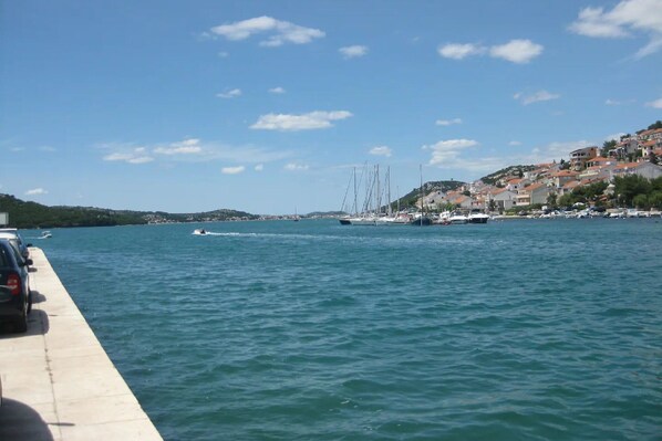 A waterfront view with boats, a pier, and buildings on a hillside.
