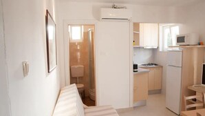 A compact hotel room with a bed, a small kitchenette, and a bathroom. - Apartments Paula - One Bedroom Apartment with Terrace 1 (Jezera)