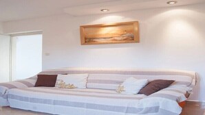 Quarto com cama grande, um quadro na parede e uma porta à esquerda.