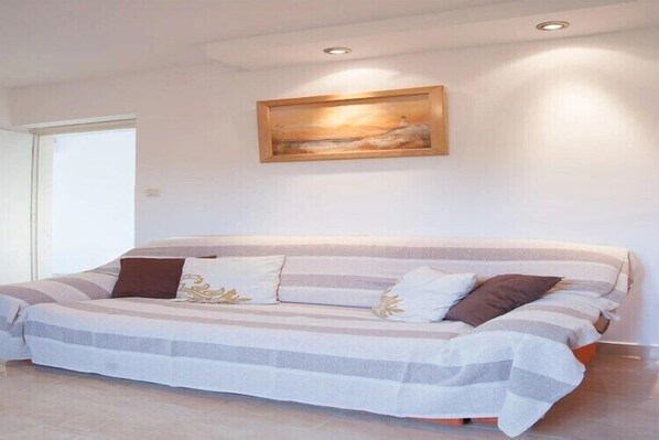 A bedroom with a large bed, a painting on the wall, and a door to the left.