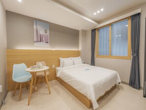 A hotel room with a bed, a desk with a chair, a small table with a basket, and a poster on the wall. - Hotel Leo Changwon Central Branch (Changwon)