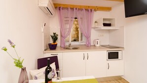 Eine kleine Küche mit Fenster, Spüle, Mikrowelle und einem flachbildfernseher, der über der Arbeitsfläche angebracht ist.