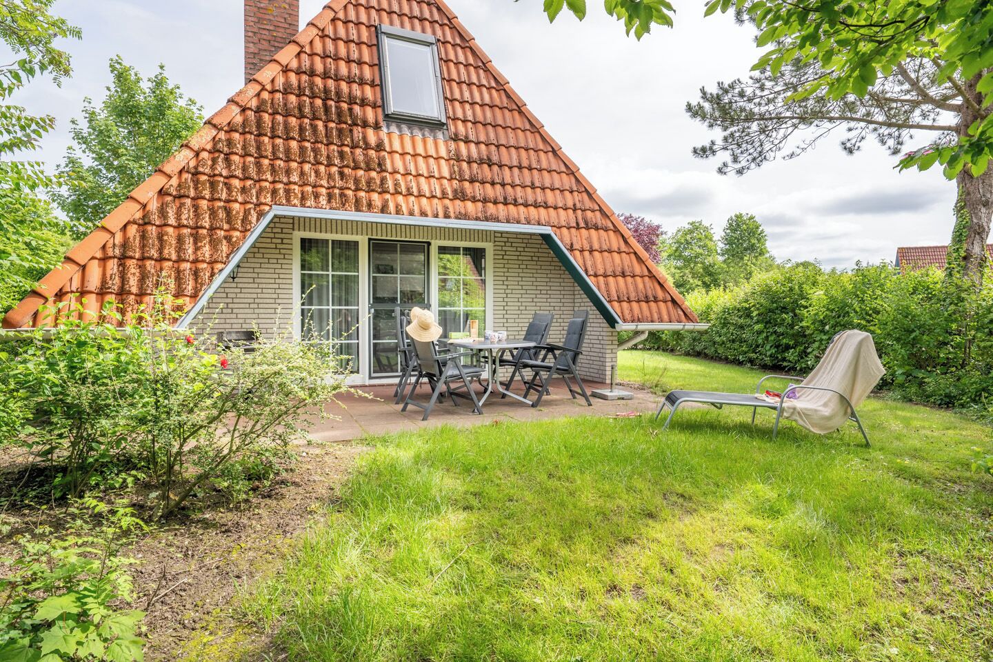 A house with a sloped roof, a patio with outdoor furniture, and a covered seating area.