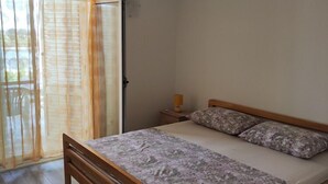Une chambre à coucher comprenant un lit, une table de chevet, une lampe et une porte-fenêtre coulissante donnant sur un balcon.