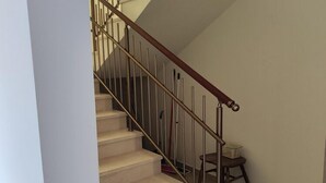 Un escalier avec une rampe en bois et des balustres en métal, menant à l’étage supérieur.