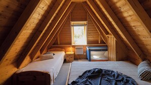 A cozy attic bedroom with a sloped ceiling, a window, a bunk bed, a desk, and a bedside table. - Vacation home Kniepsand 7 with sun terrace and comfortable. (Wurster Nordseeküste)
