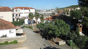 A coastal residential area with white buildings, a paved pathway, and a marina in the background.