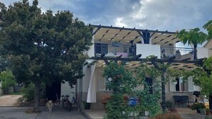 Una casa de dues plantes amb un porxo cobert, un gos i bicicletes.