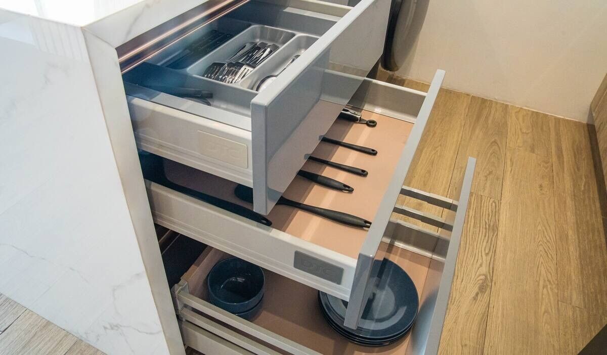A kitchen with a built-in drawer unit, a sink, and a wooden countertop.