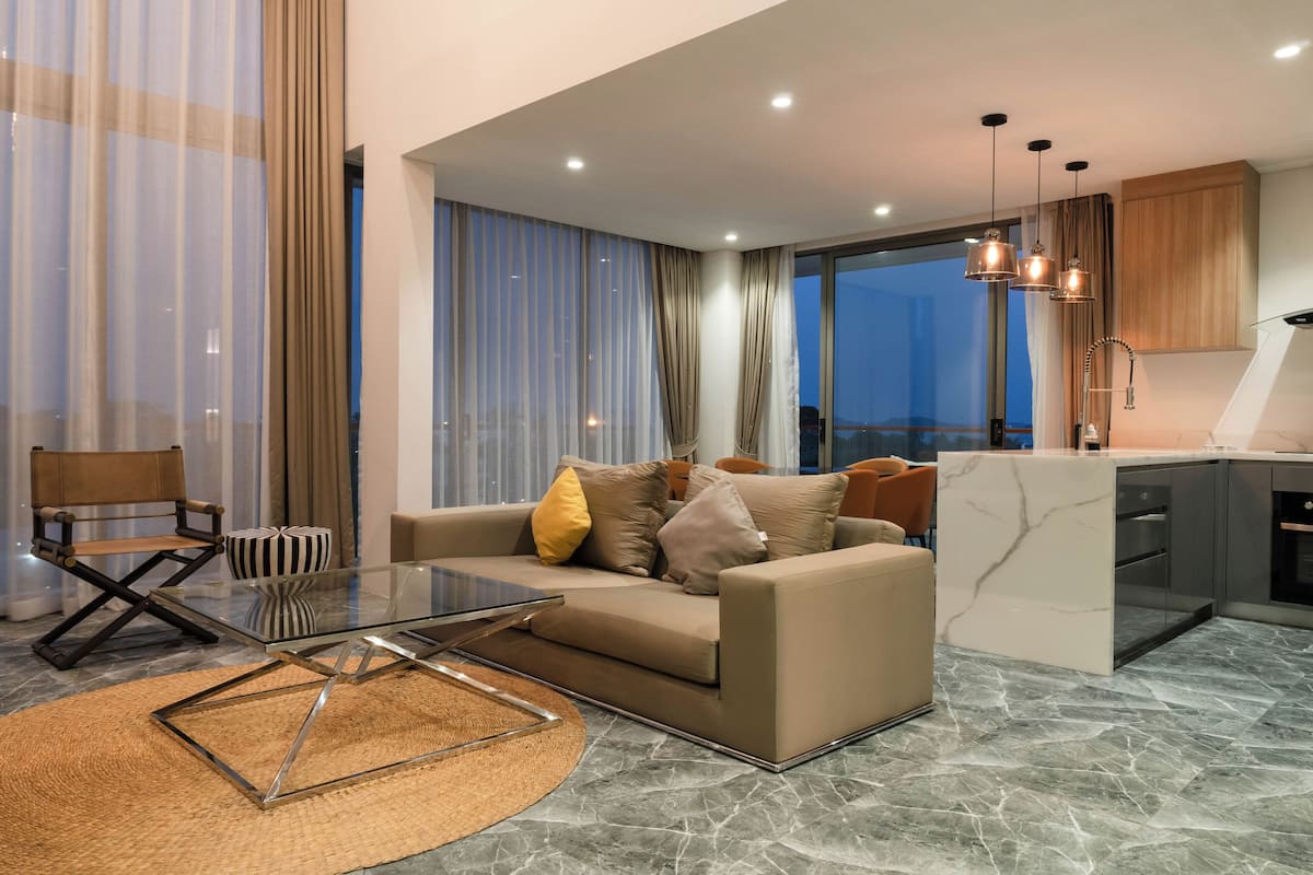Un salon moderne avec une table basse en verre, un canapé beige et une vue sur la ville.