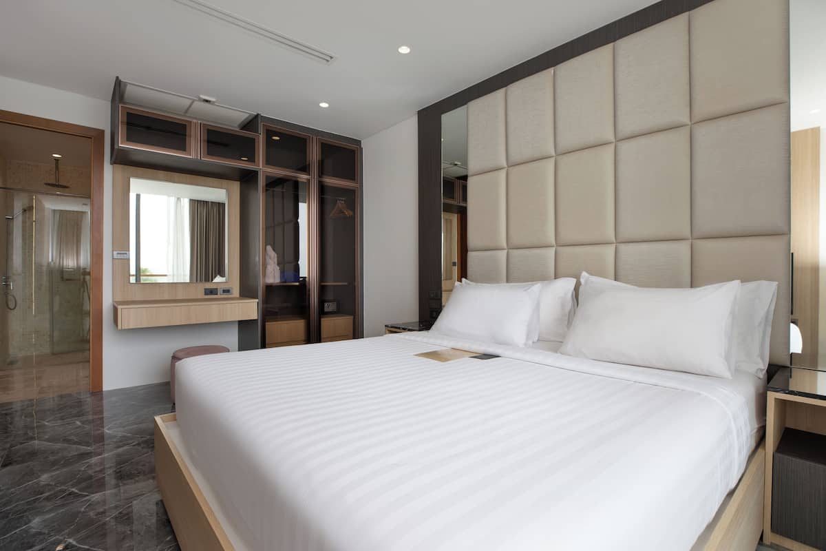 Une chambre d’hôtel moderne dotée d’un grand lit, d’une armoire intégrée, d’un miroir et d’un espace douche.