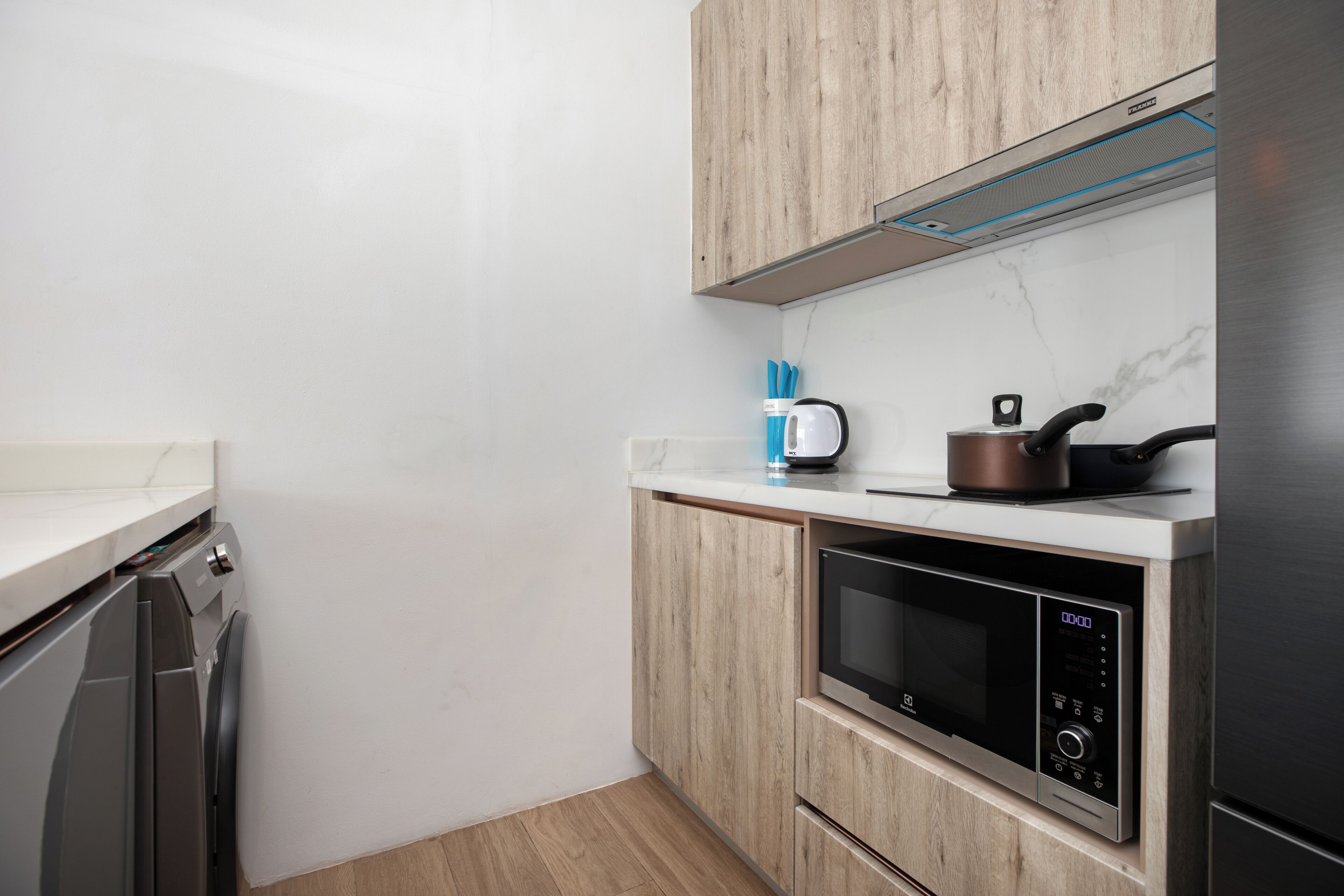 A compact kitchen with a microwave, a kettle, and a dishwasher.