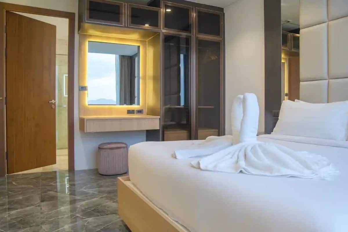 Une chambre d’hôtel moderne dotée d’un grand lit, d’une armoire intégrée, d’une coiffeuse avec miroir et offrant une vue sur les montagnes.