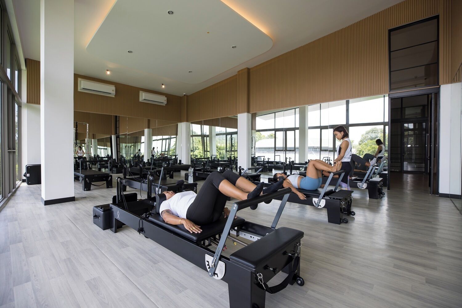 A modern gym with Pilates equipment, large windows, and a clean, spacious layout.