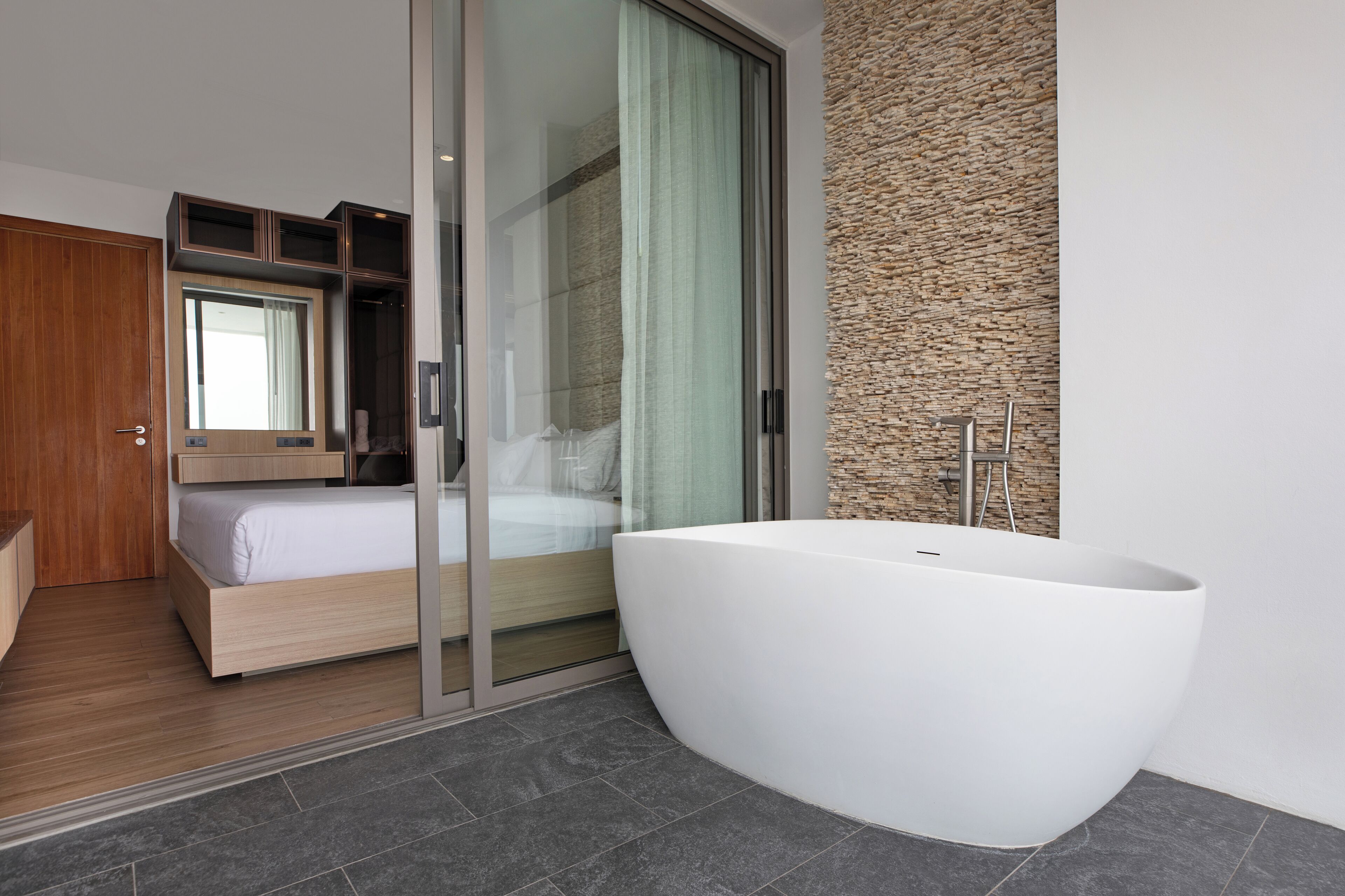 A modern bathroom with a large freestanding bathtub, a glass shower enclosure, and a wooden vanity.
