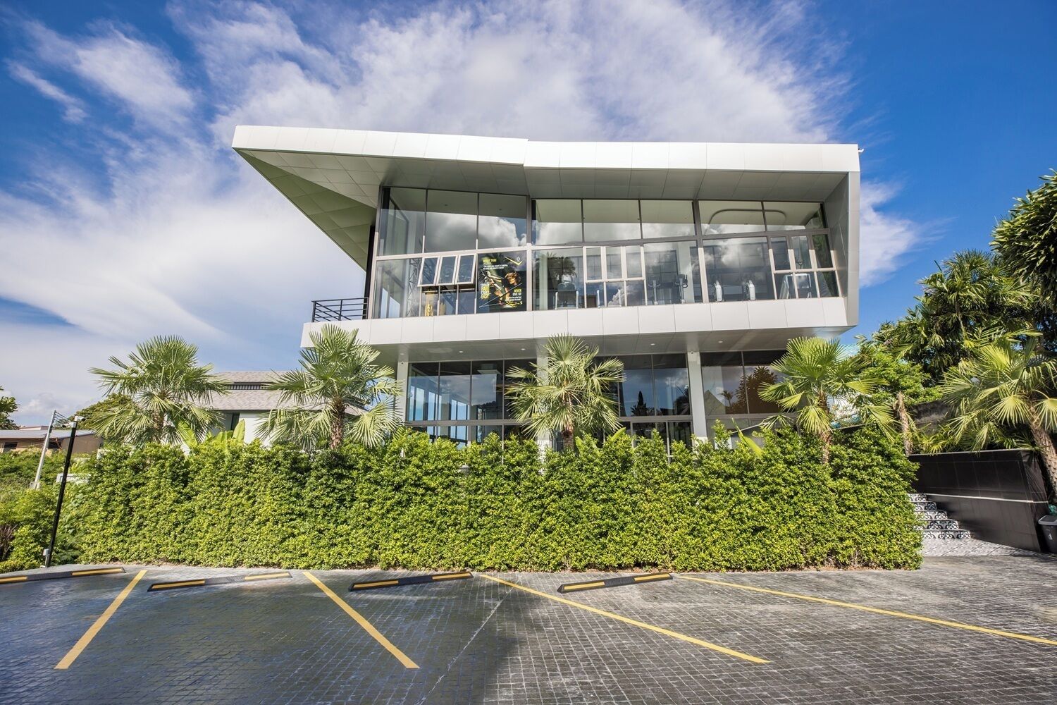Un edificio moderno con tejado plano, grandes ventanales y un balcón.