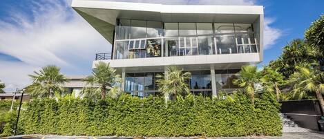 Un edificio moderno con tejado plano, grandes ventanales y un balcón.