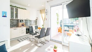 Een moderne keuken met witte kasten, een magnetron en een eethoek met zwarte stoelen.