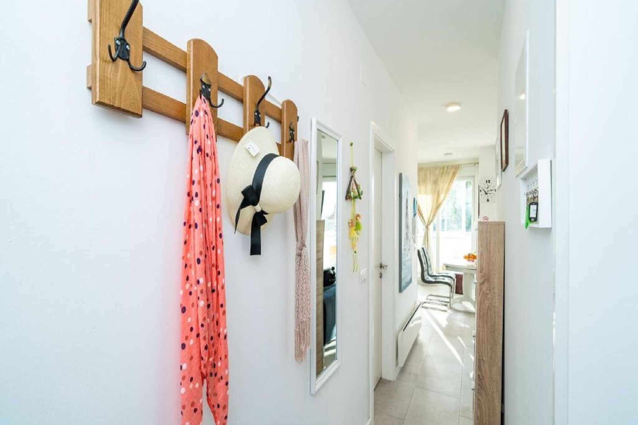 A hallway with a coat rack holding hats and a pink polka dot garment.