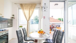 Een moderne keuken met een eethoek, een klok en uitzicht op het balkon.
