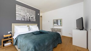 Ein modernes Hotelzimmer mit einem großen Bett, einem Flachbildfernseher, einem Schreibtisch und einem Spiegel.