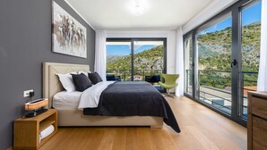 Ein modernes Schlafzimmer mit Bett, Nachttisch und einem großen Fenster mit Balkon.