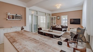 A spacious living area with a large wooden dining table, a comfortable sofa set, and a flat-screen TV mounted on the wall. - Villa Ponar with Swimming Pool (Kuciste)