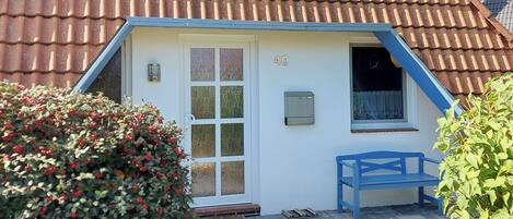 A small house with a white exterior, a blue roof, and a number '40' on the wall.