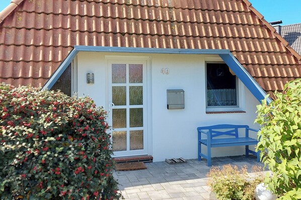 A small house with a white exterior, a blue roof, and a number '40' on the wall.